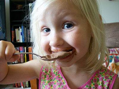 little girl messing with chocolate mousse -    