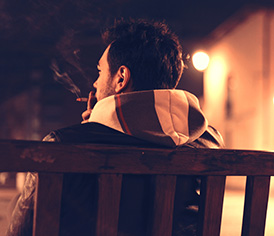 Man alone smoking in bench
